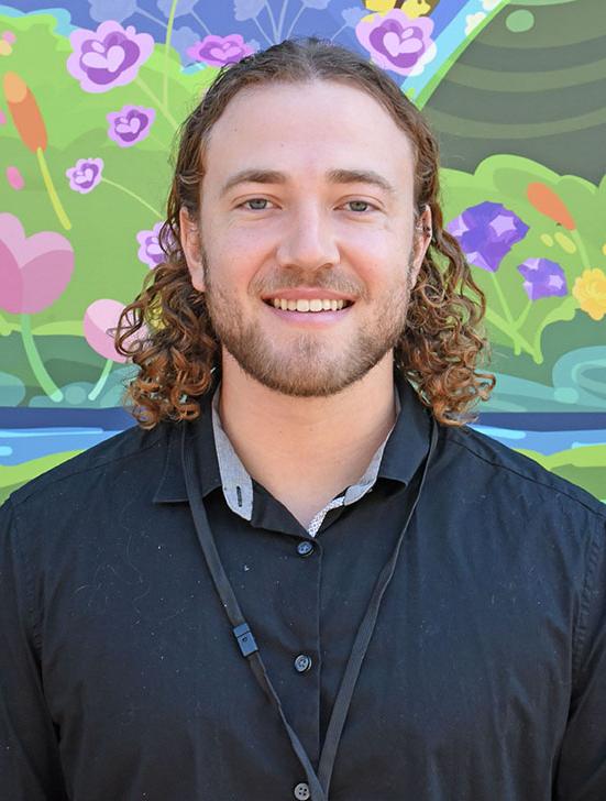 A person with curly hair and facial hair smiling.