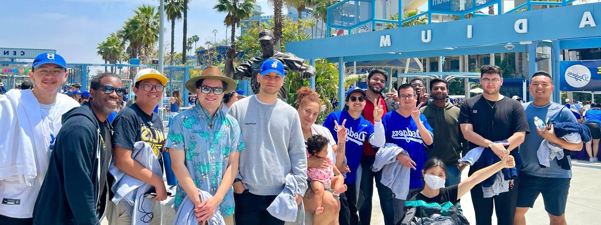 Group of men and women standing and smiling in front of a blue structure